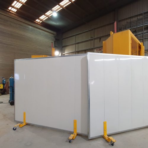 Sonic System mobile acoustic panels with white faces and yellow castor supports positioned around industrial equipment at Newcrest Mining.