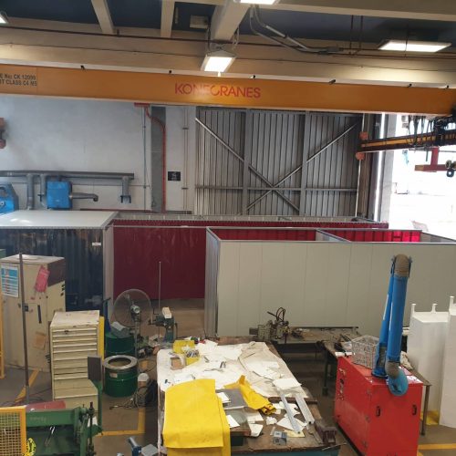 Flexshield acoustic welding bay with Sonic System acoustic modular panel walls and red Weldflex™ strip curtains inside a defence workshop.