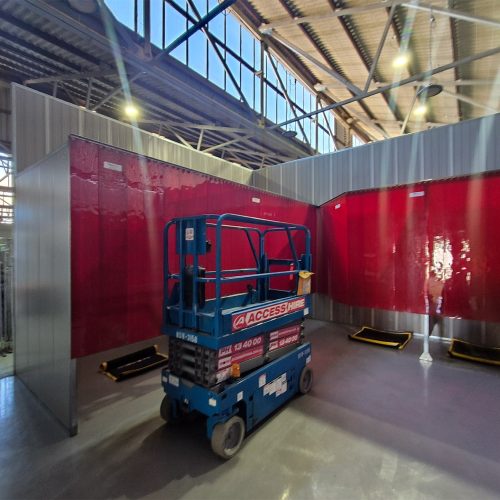 Flexshield acoustic welding bays with Weldflex strip curtains and Sonic System acoustic modular panels installed inside an industrial workshop.