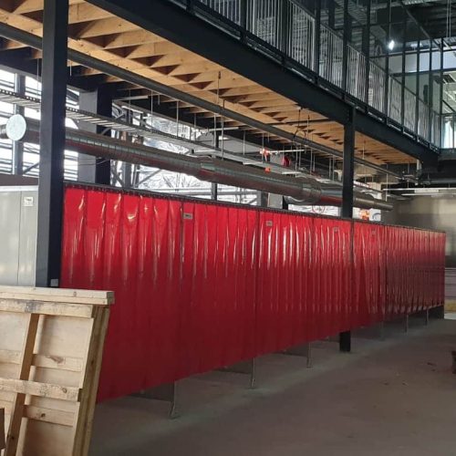 Flexshield acoustic welding bays with red Weldflex™ strip curtains and Sonic System acoustic modular panel walls.