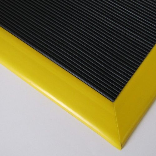 Close-up of a black corrugated FlexWeld floor mat with a yellow ramped border