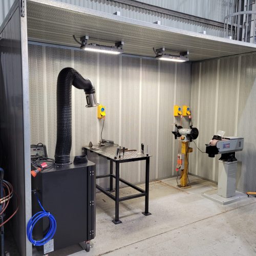 Safe welding fume extraction unit with flexible arm beside a welding table in an industrial workshop