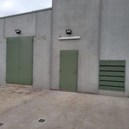 Green Sonic Access acoustic doors and Sonic Series acoustic louvre installed in a concrete industrial building.