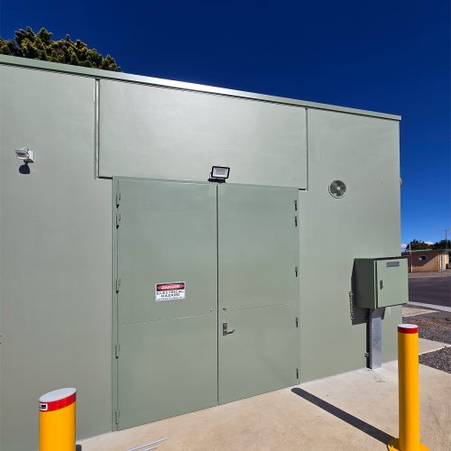 Large green Sonic Access acoustic double doors installed on the exterior of an industrial building.