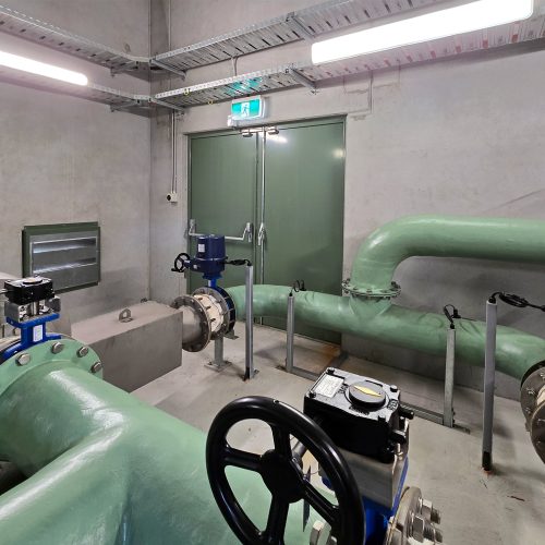 Green Sonic Access acoustic doors installed in a plant room with large pipework and valves.