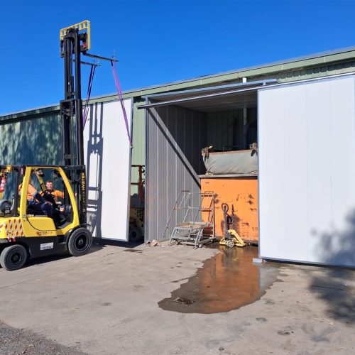 Sonic acoustic enclosure with large sliding doors at an industrial workshop