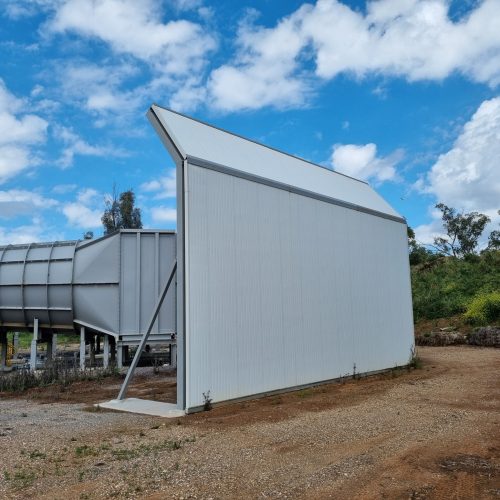 Tall acoustic wall beside industrial ductwork and processing equipment at North Parkes Mine