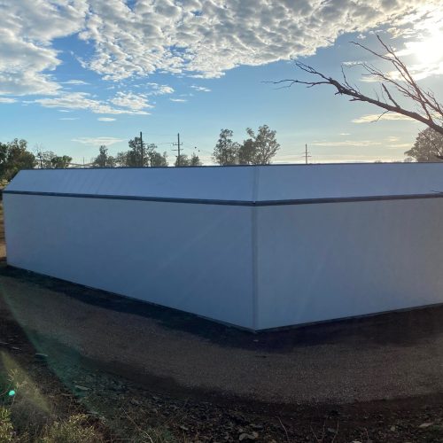 Large enclosed acoustic wall structure at North Parkes Mine under a blue sky