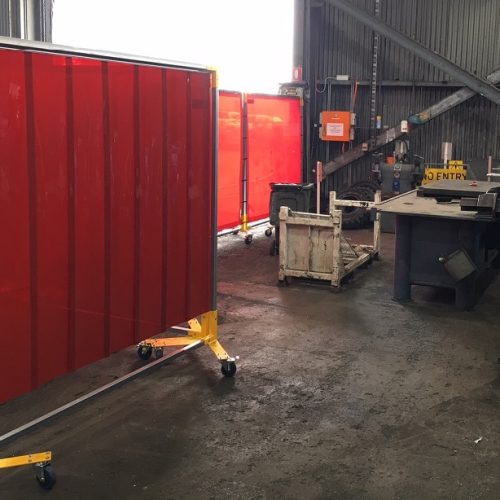 Weldflex™ mobile screens with red welding strips in an industrial fabrication workshop