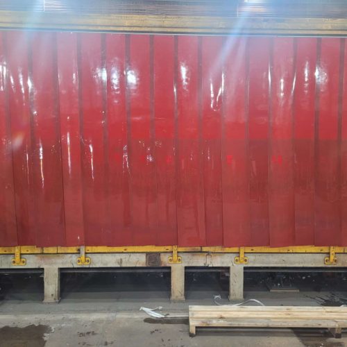 Red Weldflex™ Strip Curtains installed along a fabrication bay inside an industrial workshop.