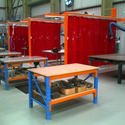 Red Weldflex™ Strip Curtains installed between fabrication benches to create separate work bays.
